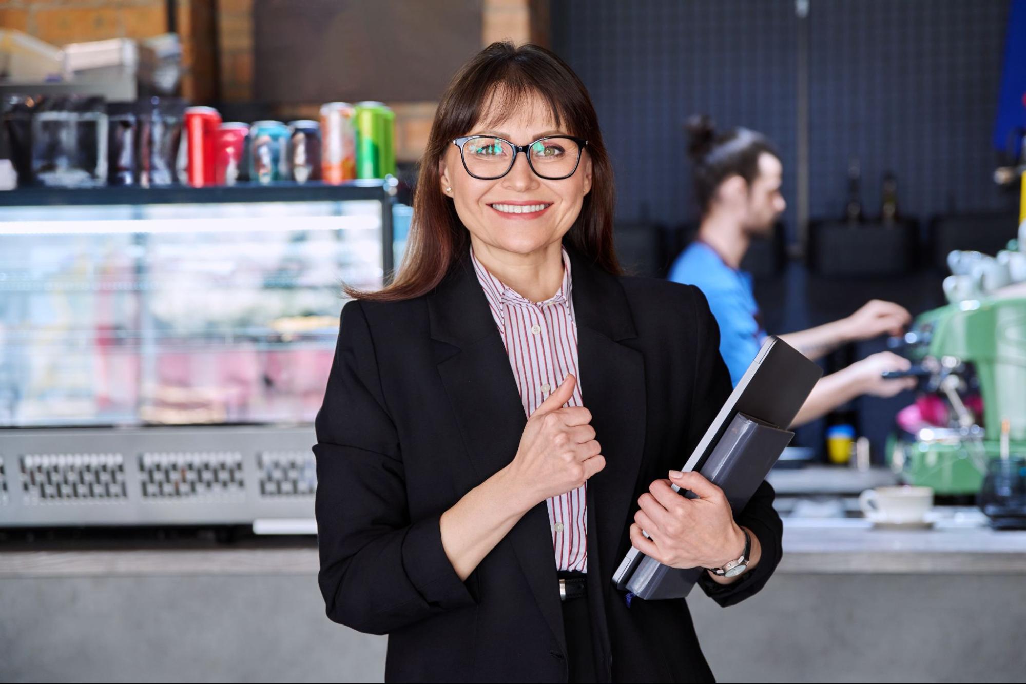 Smiling business woman holding a folder and holding a thumbs up.