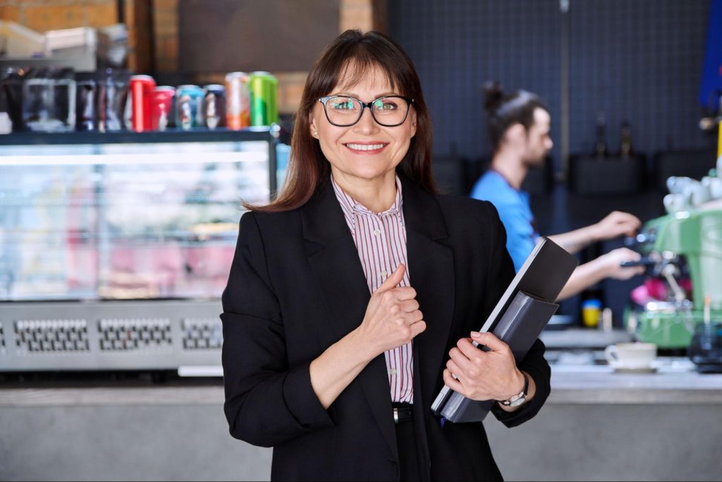 Smiling business woman holding a folder and holding a thumbs up. 