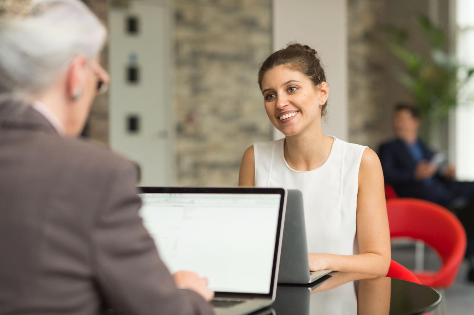 A smiling young businesswoman consults with a business consultant about company registration at the office lobby.