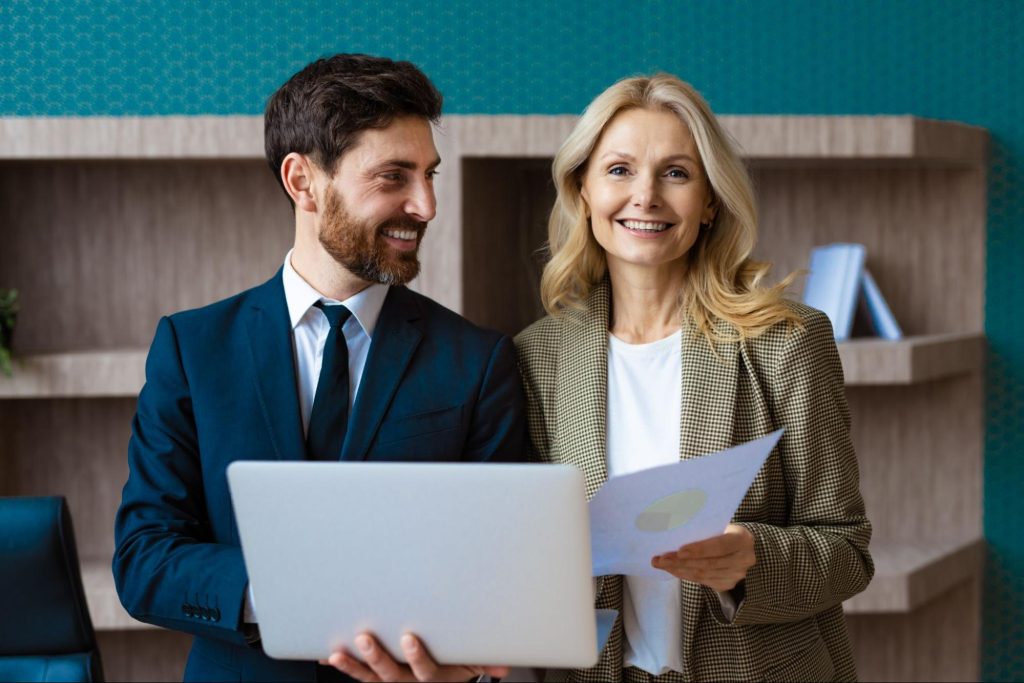 A business man and woman with a computer and paperwork. 